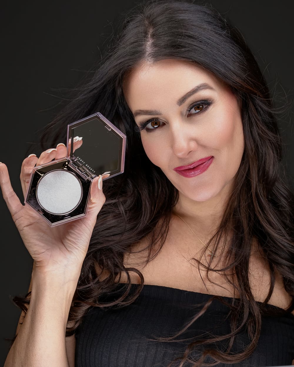 Beauty shot holding a powder compact to camera