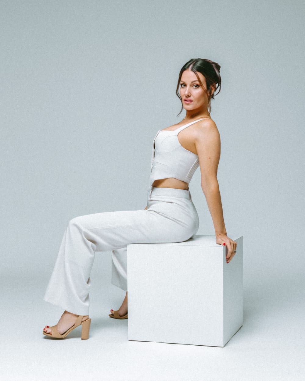 Seated studio pose in white tailored separates